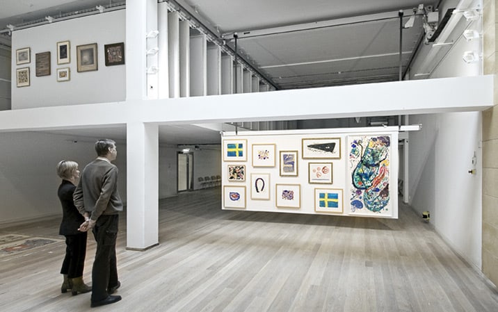 Tavlor visas på hängande presentationsställ i galleri