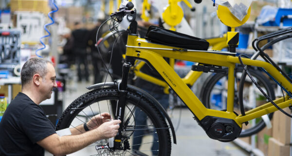 Montör vid gul elcykel i hängande lastbärare